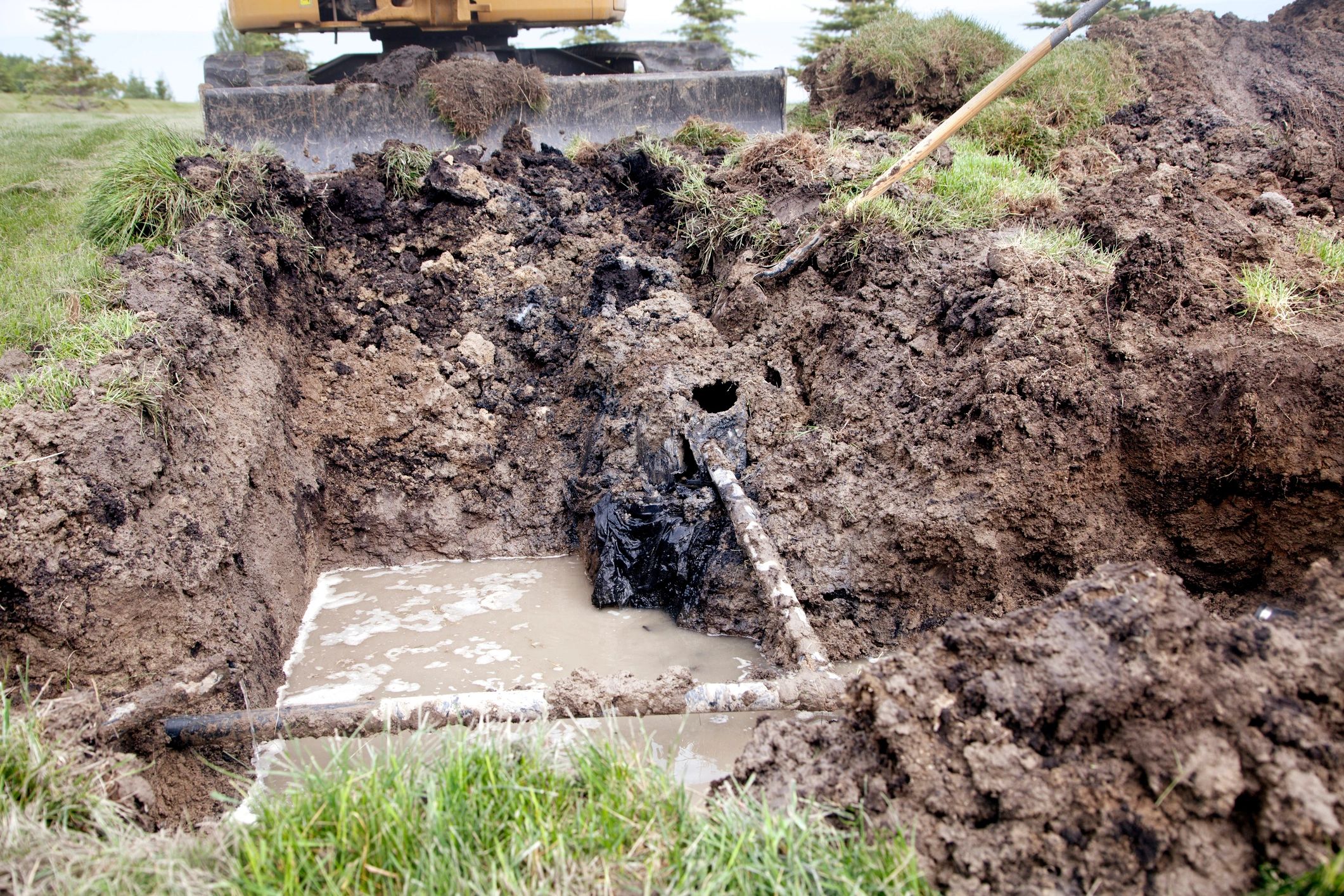 Excavated trench showing broken drain pipe repair work in Illinois
