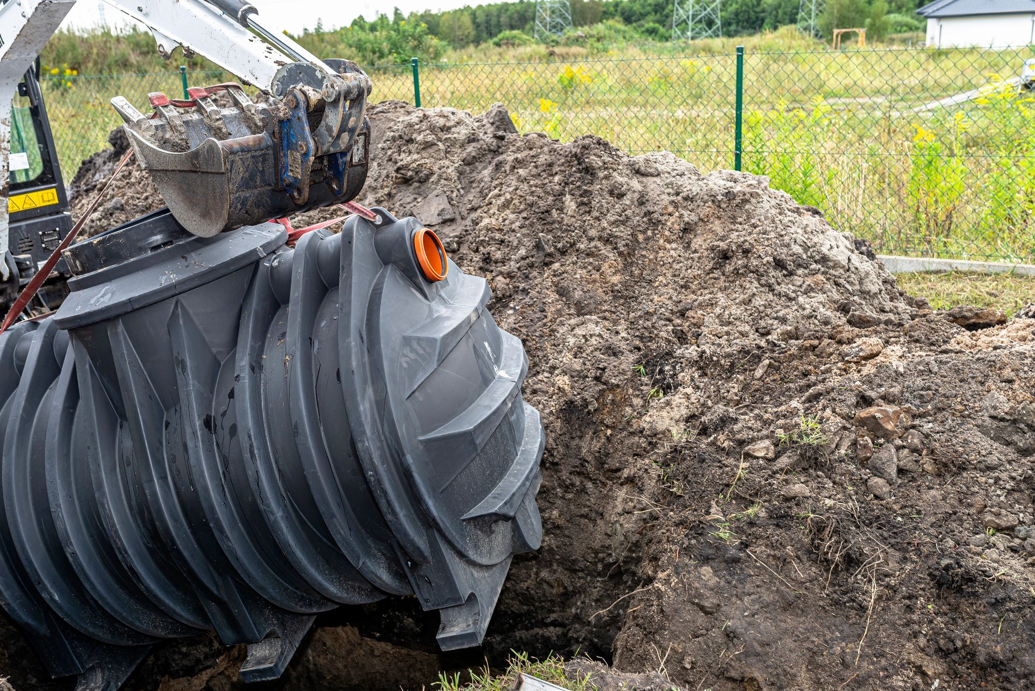Excavator lifting a septic tank during septic system installation in Illinois